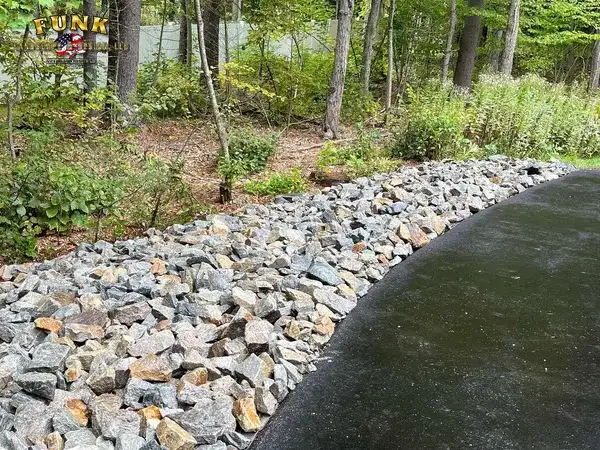 Stone drainage swale built during site preparation in Webster, MA by Funk Landscape & Design