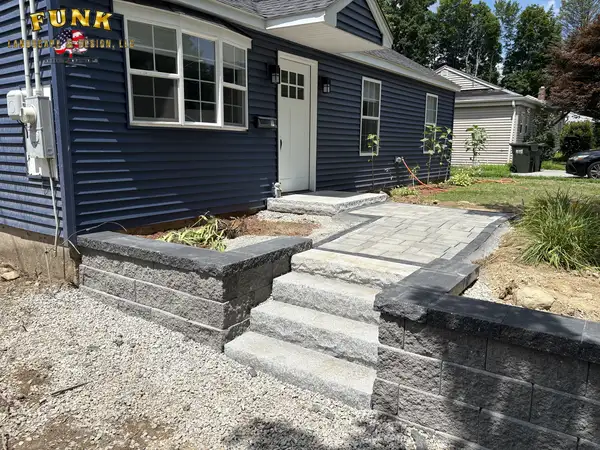 Natural stone wall with granite steps at the front entry beside a fresh gravel bed