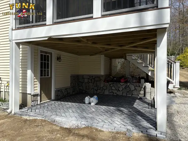 Paver patio under a deck during installation with materials staged