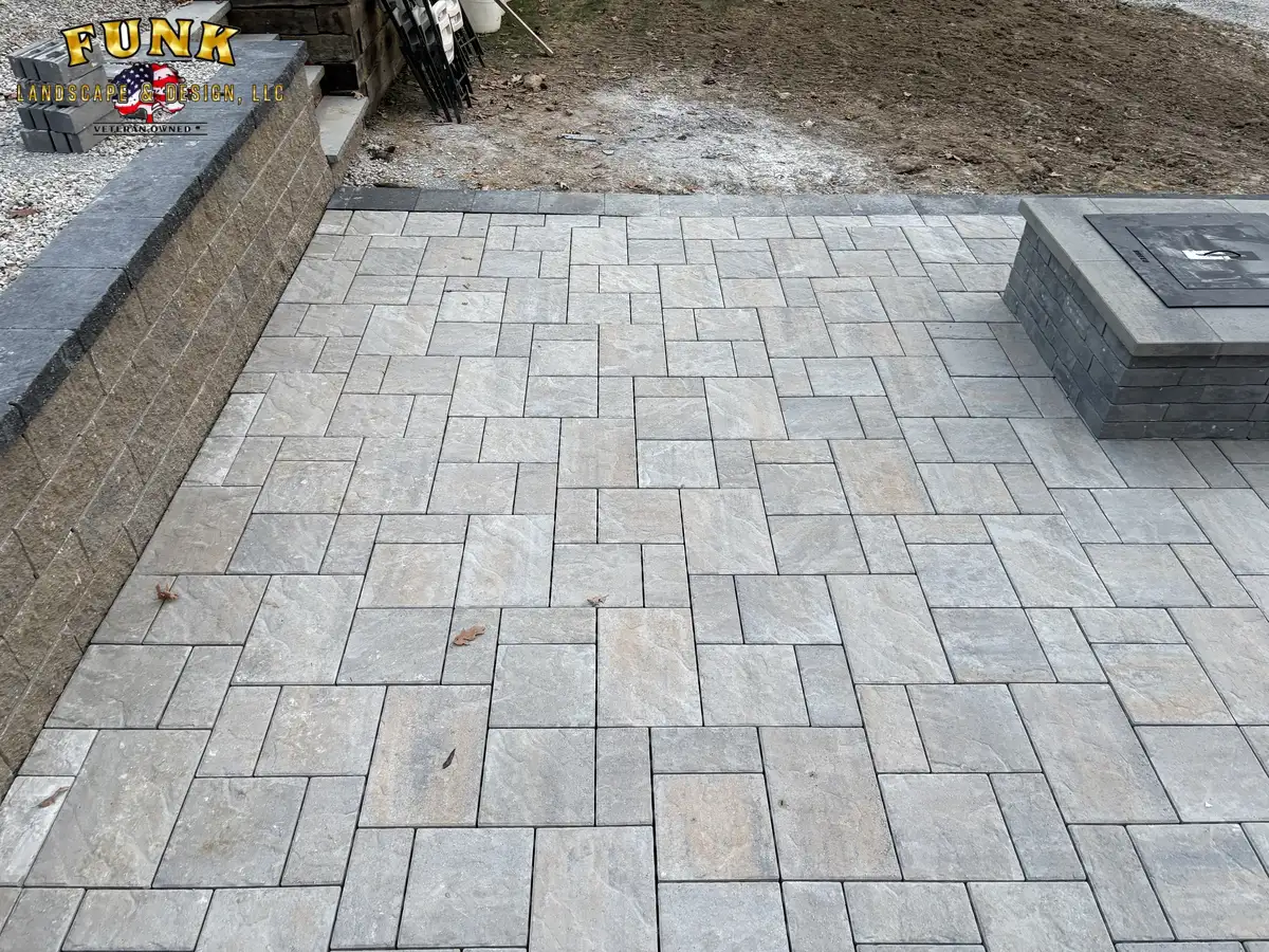 Finished large-format paver patio with fire pit and retaining wall