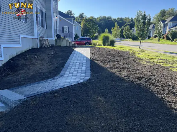 New paver walkway with dark border running through the graded yard