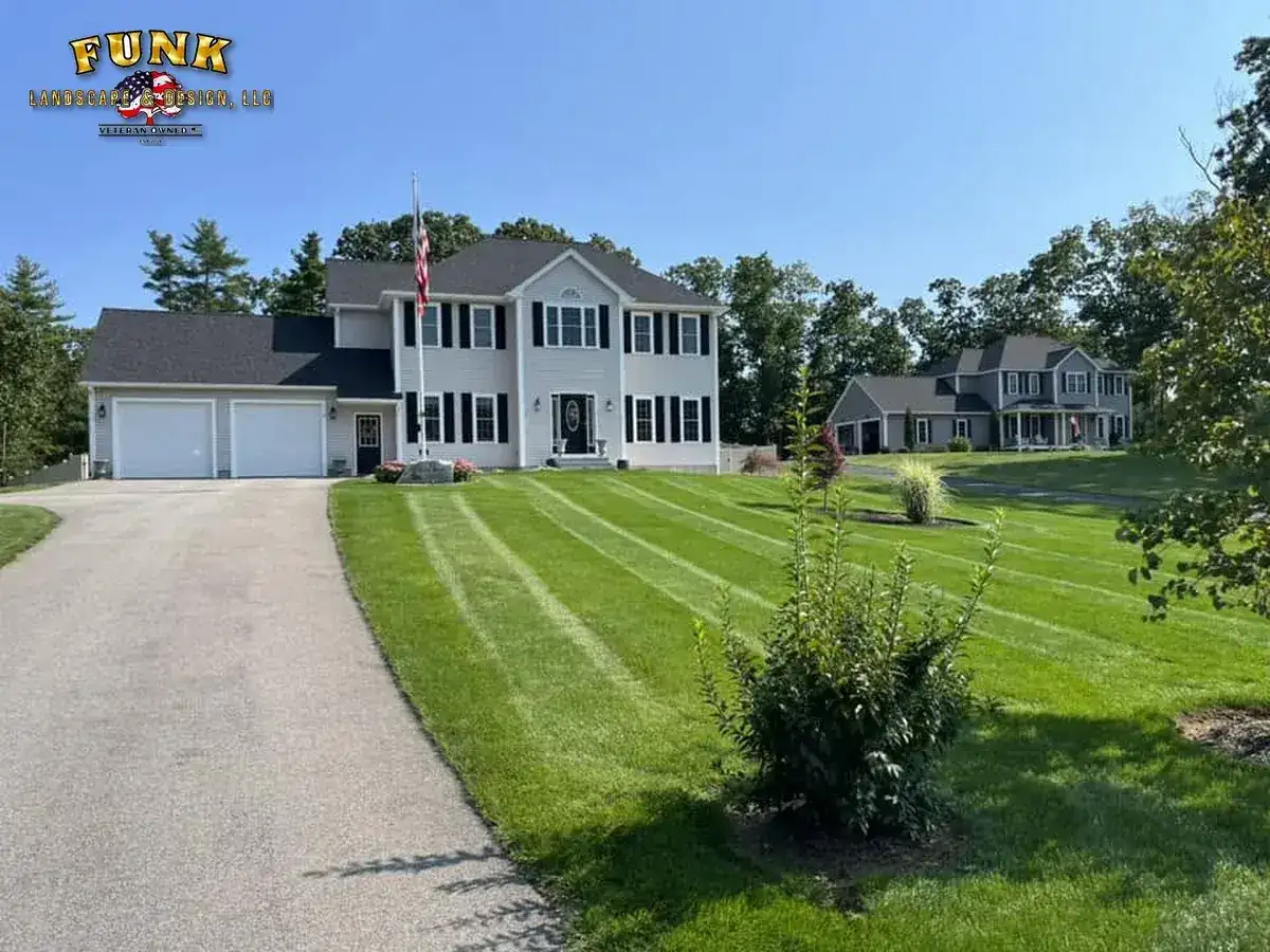 Striped lawn and long drive at a Charlton, MA property maintained by Funk Landscape & Design
